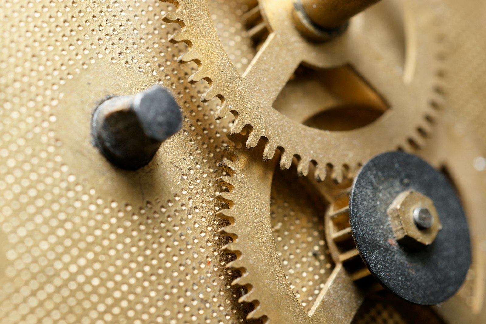 Macro view of interlocking brass clock gears on a textured metal plate