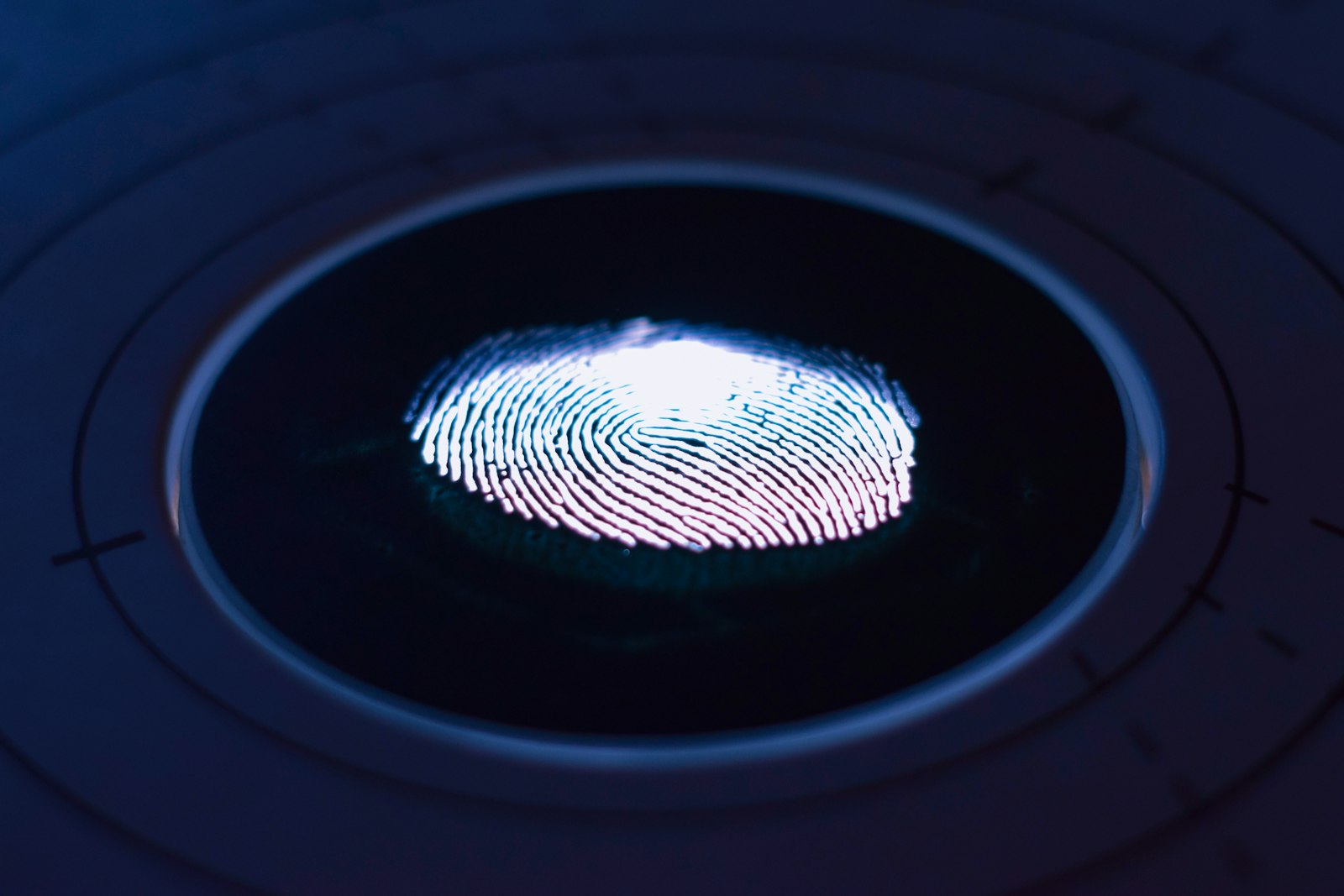 A glowing fingerprint lit up on a dark circular scanner