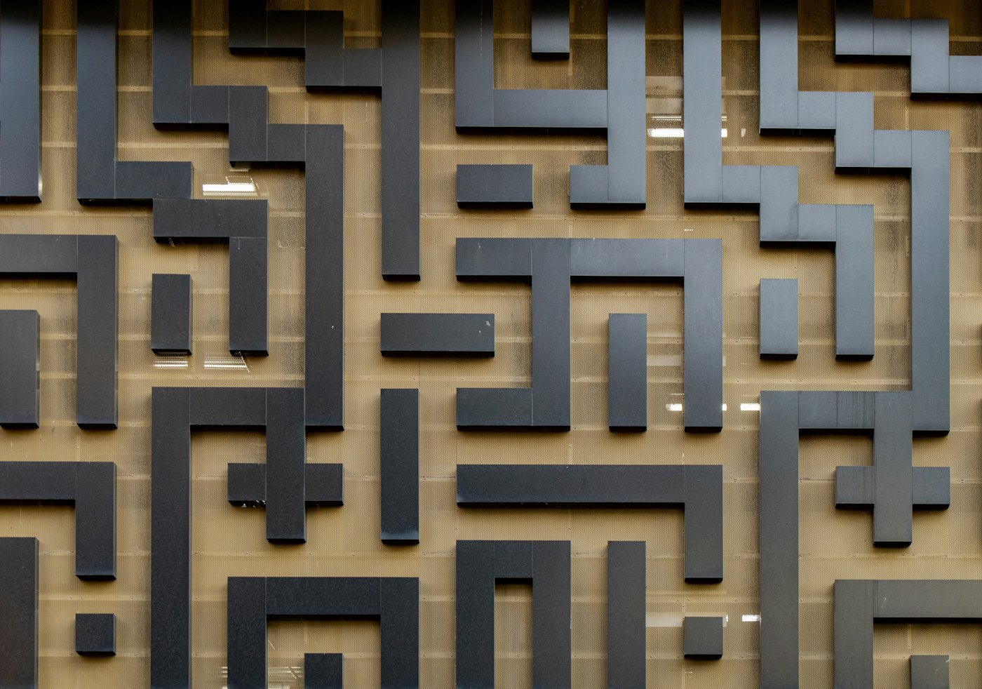 Overhead view of an abstract black geometric maze pattern on a gold wall
